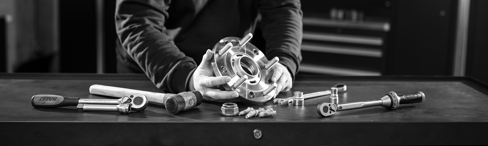 Mechanikerhände montieren Radnabe mit Werkzeugen auf Werkbank.