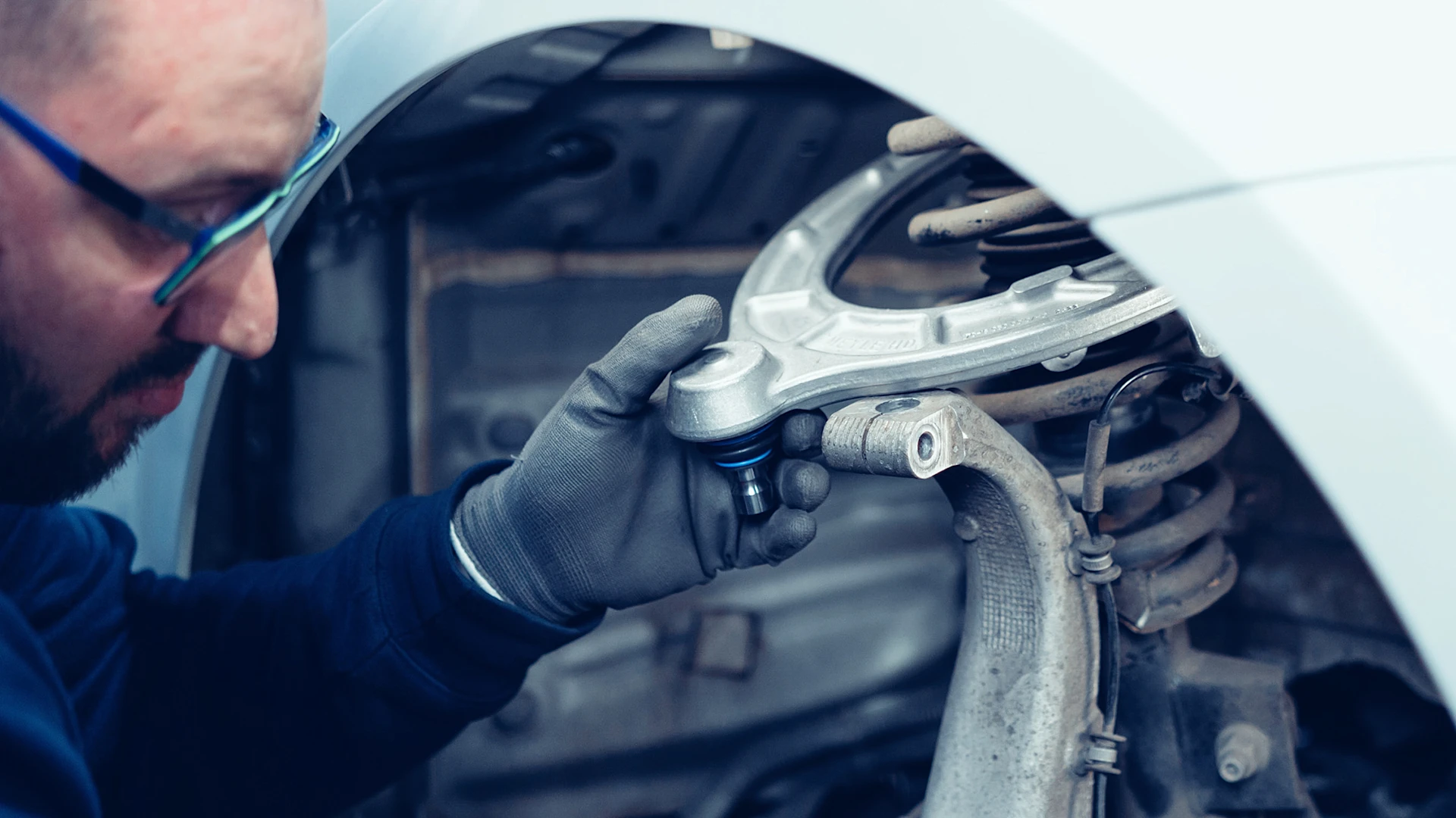 A person checks an installed control arm.