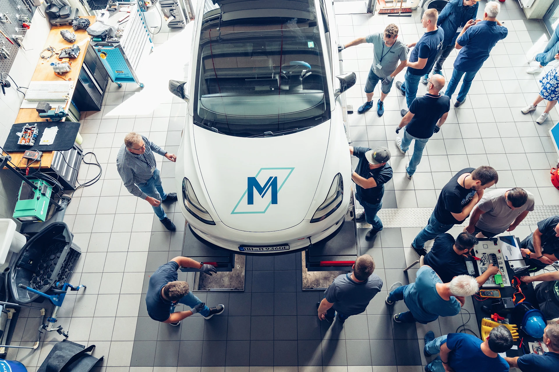 EV Training in der MEYLE Werkstatt an einem Elektroauto. Man sieht das Auto aus der Vogelperspektive und drum herum ein paar Teilnehmer des Trainings.