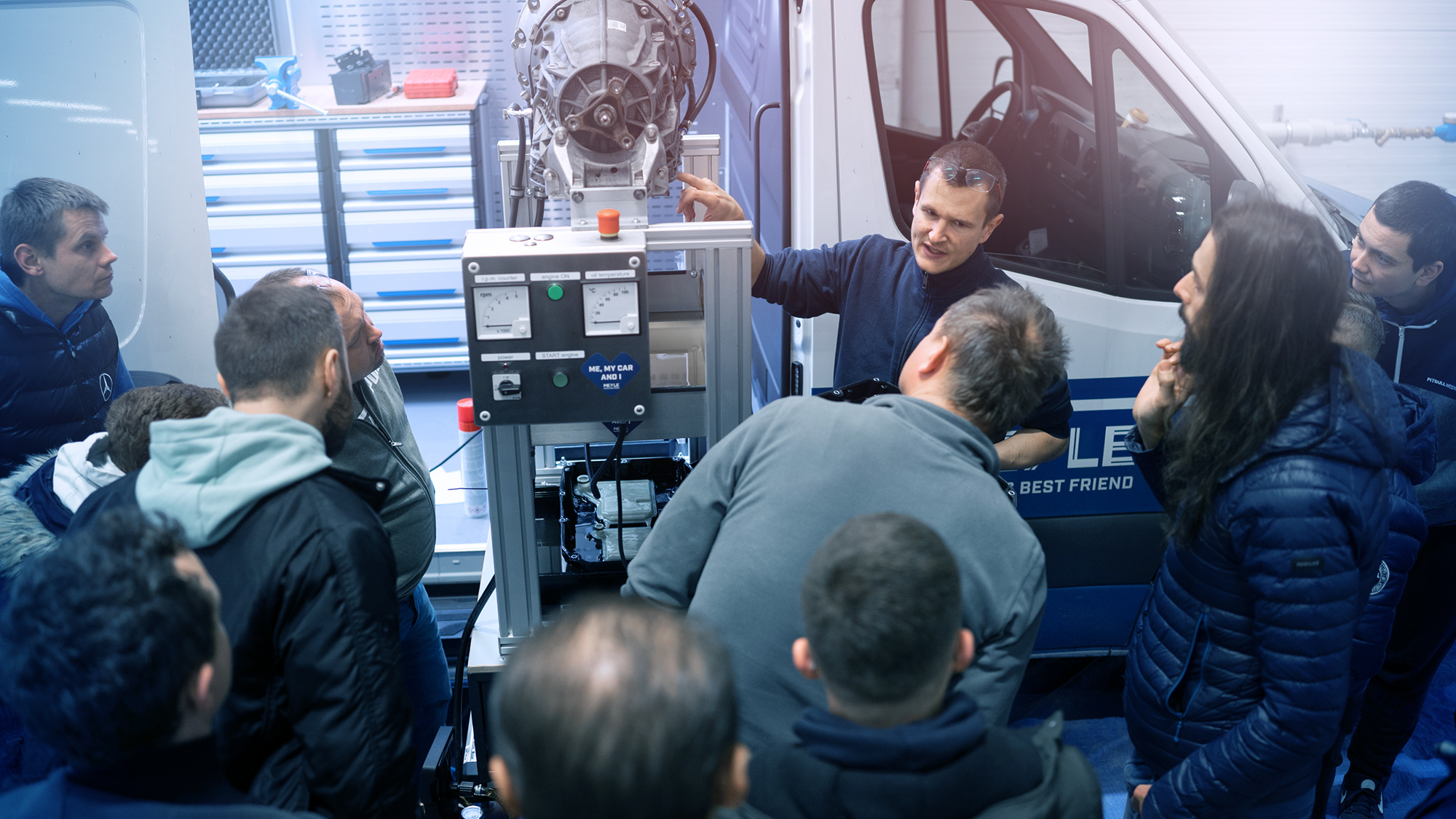 A person explains something to several people using a device on a van.