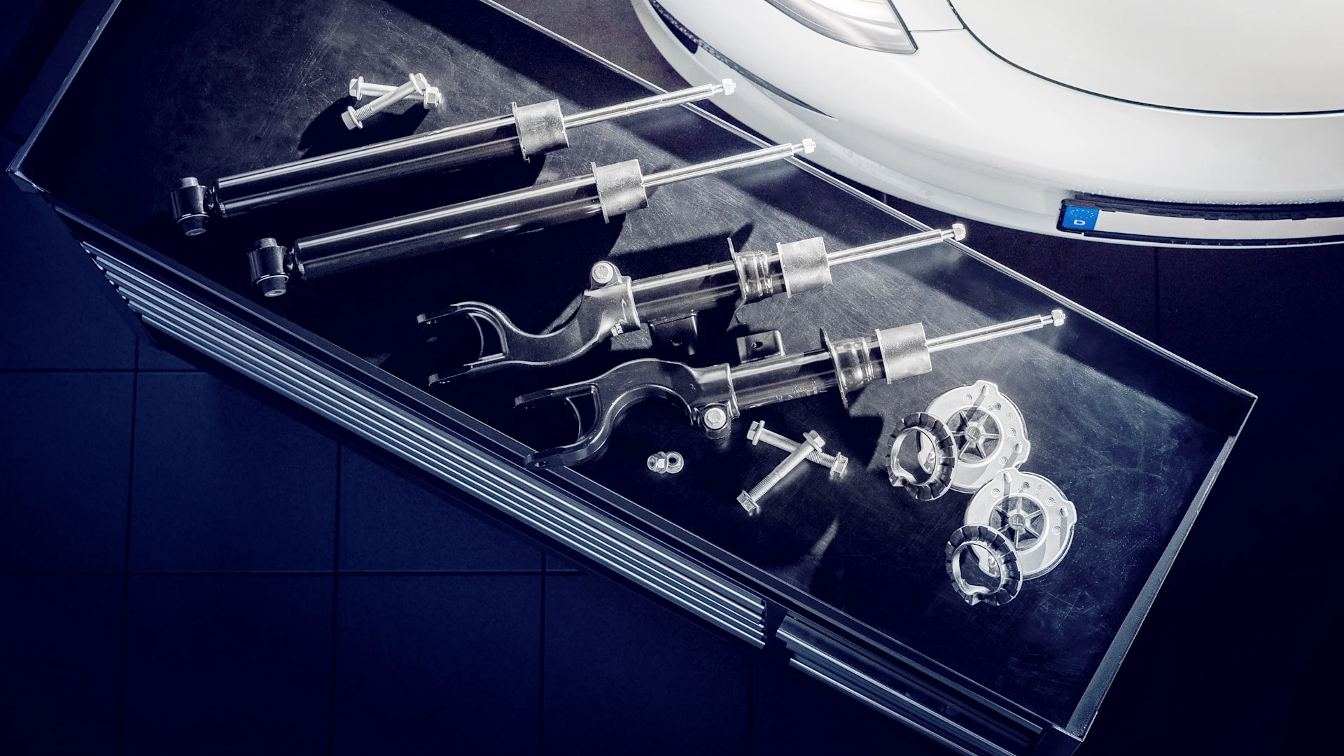 Photo of MEYLE PD shock absorbers for Tesla, taken from above in a workshop; a small part of a Tesla can still be seen.