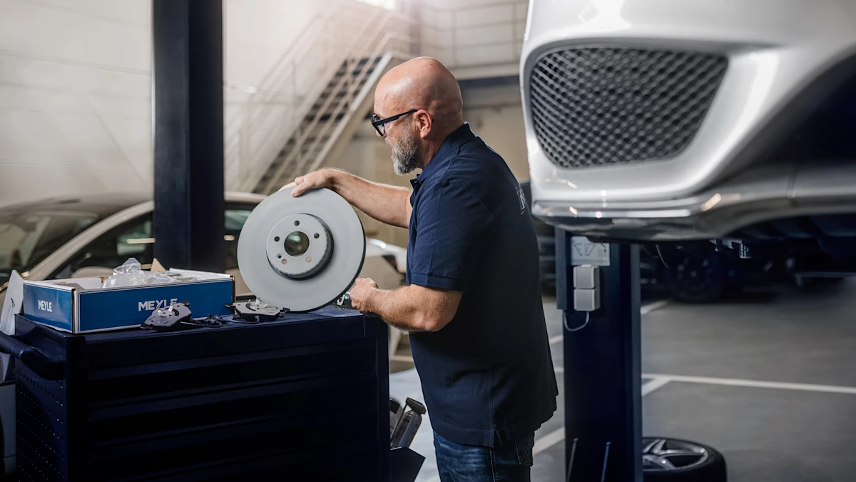Mechanic, unpacks a brake disk from a box on a lifting platform.