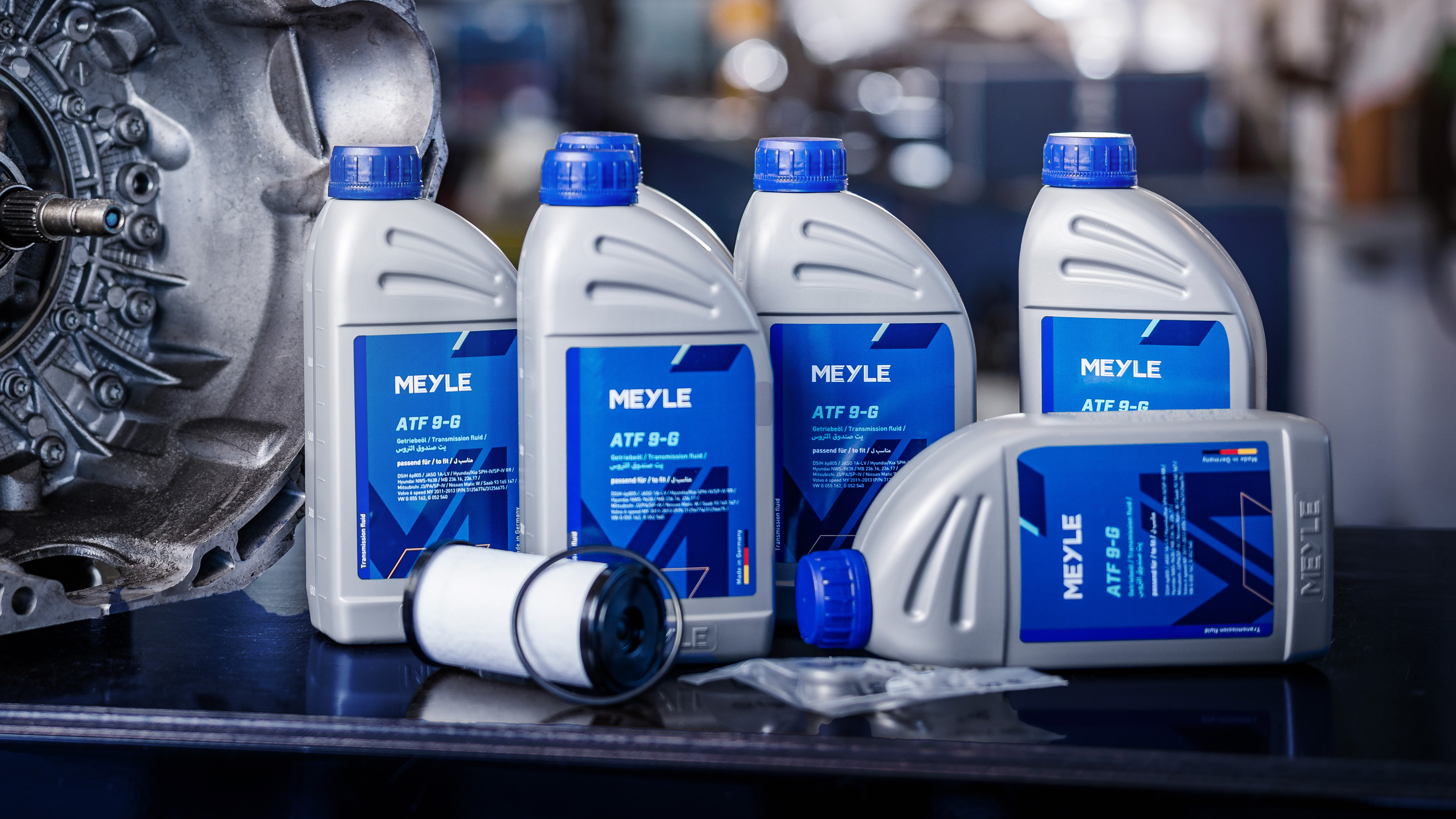 Photo of MEYLE engine oil bottles with the new labels in a workshop setting.