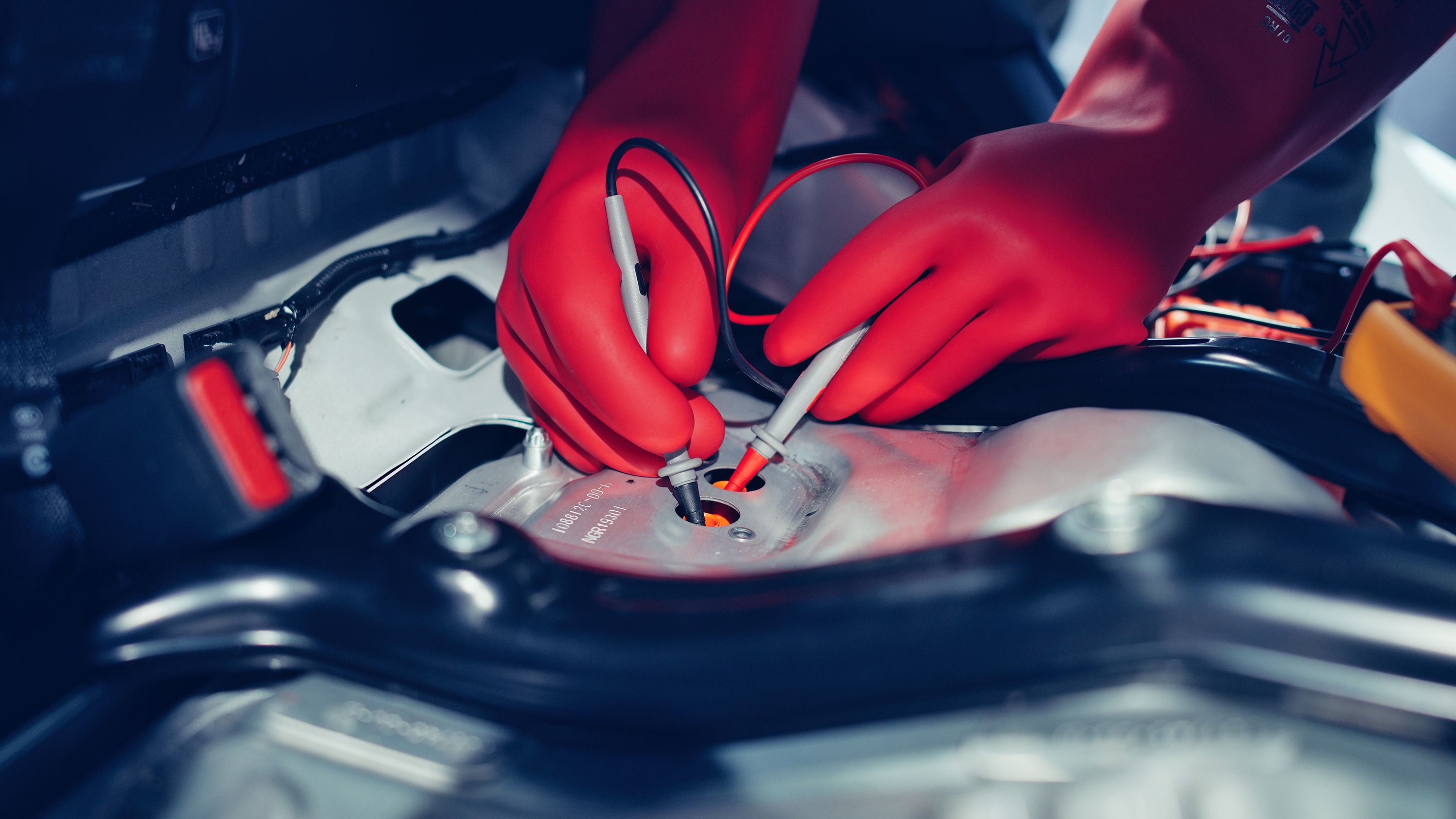 Close-up of hands in high-voltage protective clothing repairing something on an electric motor.