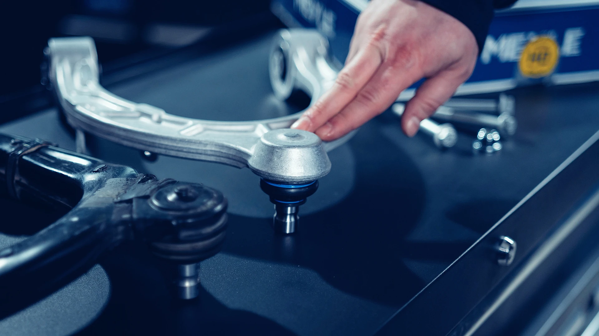Fingers point to a spot on a MEYLE HD control arm.