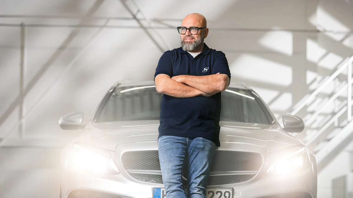 Person leaning against a car, headlights shining into the camera.