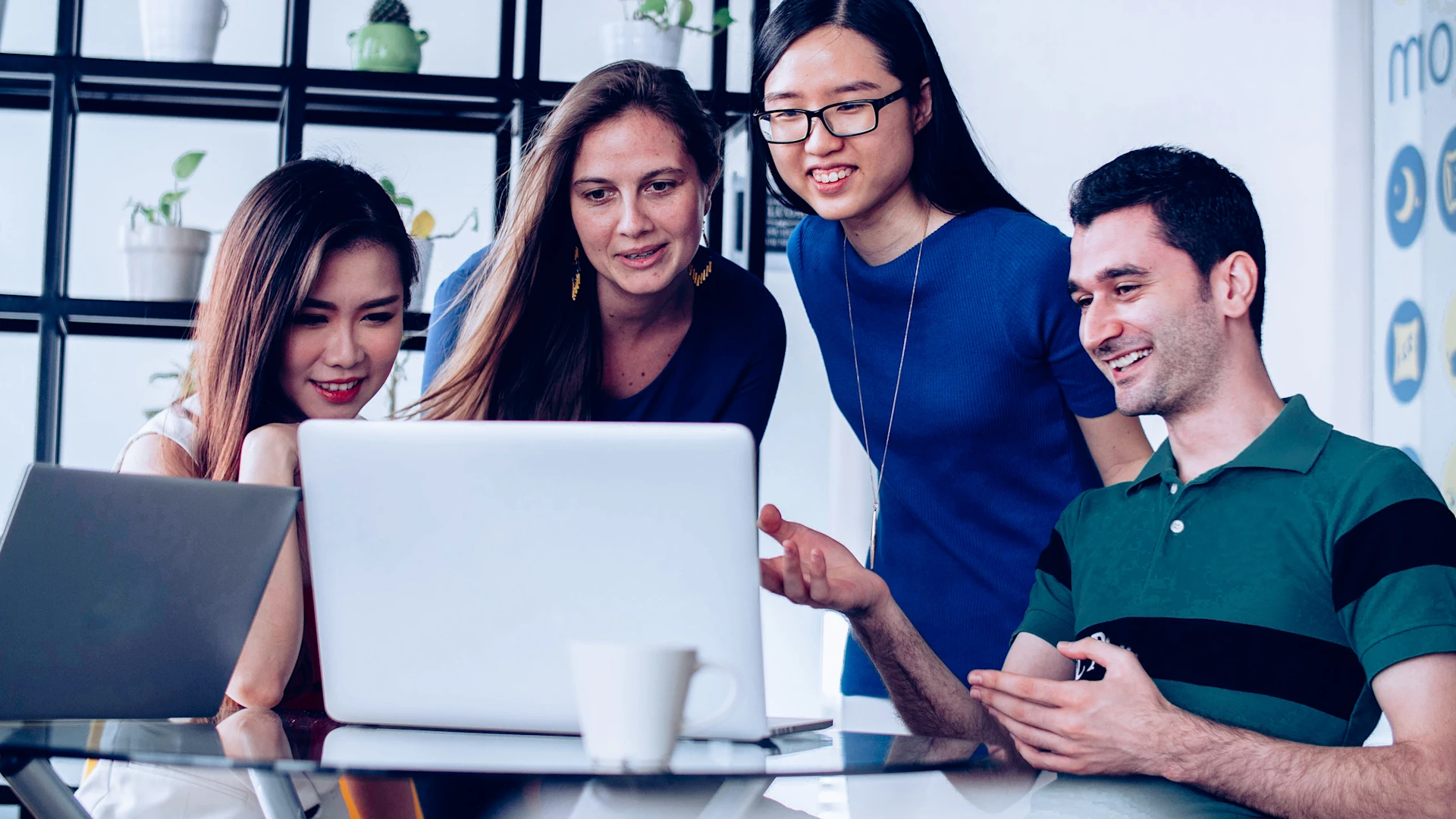Picture of four people rejoicing and looking at a laptop screen.