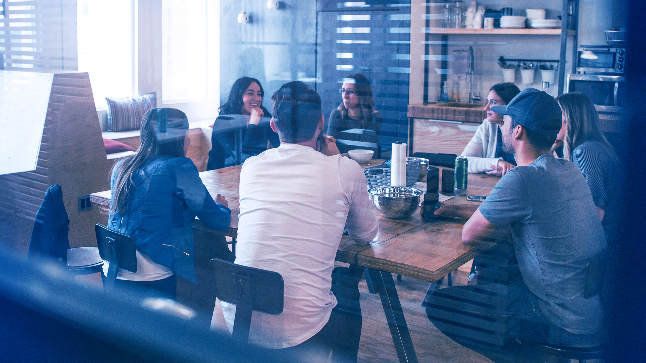 Sieben junge Personen die um einen Tisch herum sitzen.