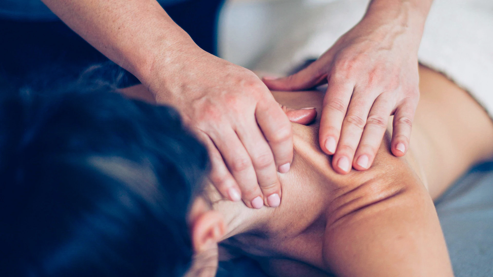 A close-up of hands massaging a neck.