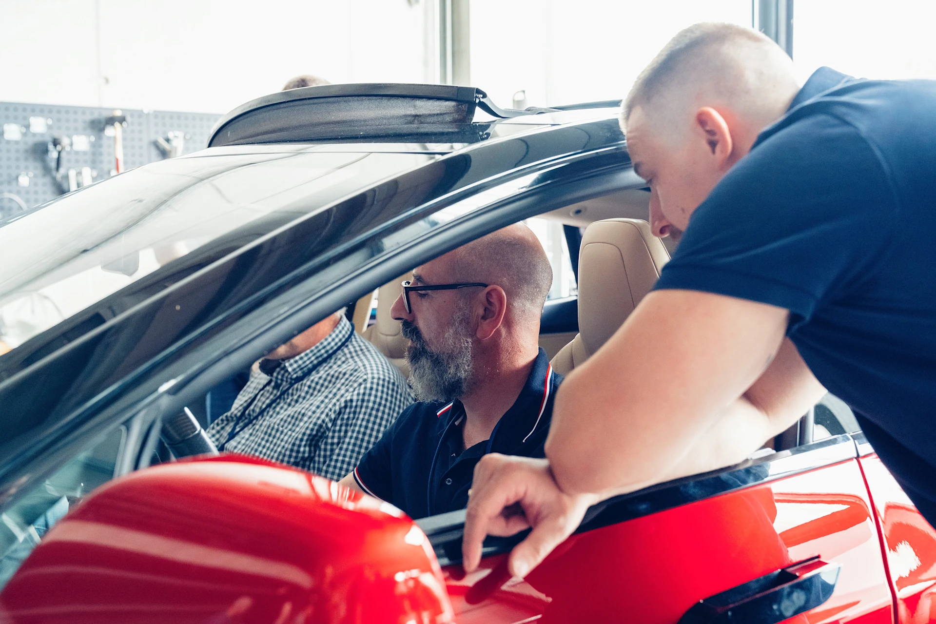 EV Training in MEYLE Werkstatt. Trainingsteilnehmer sitzen in einem Elektroauto und lassen sich etwas von einem Trainer erklären.