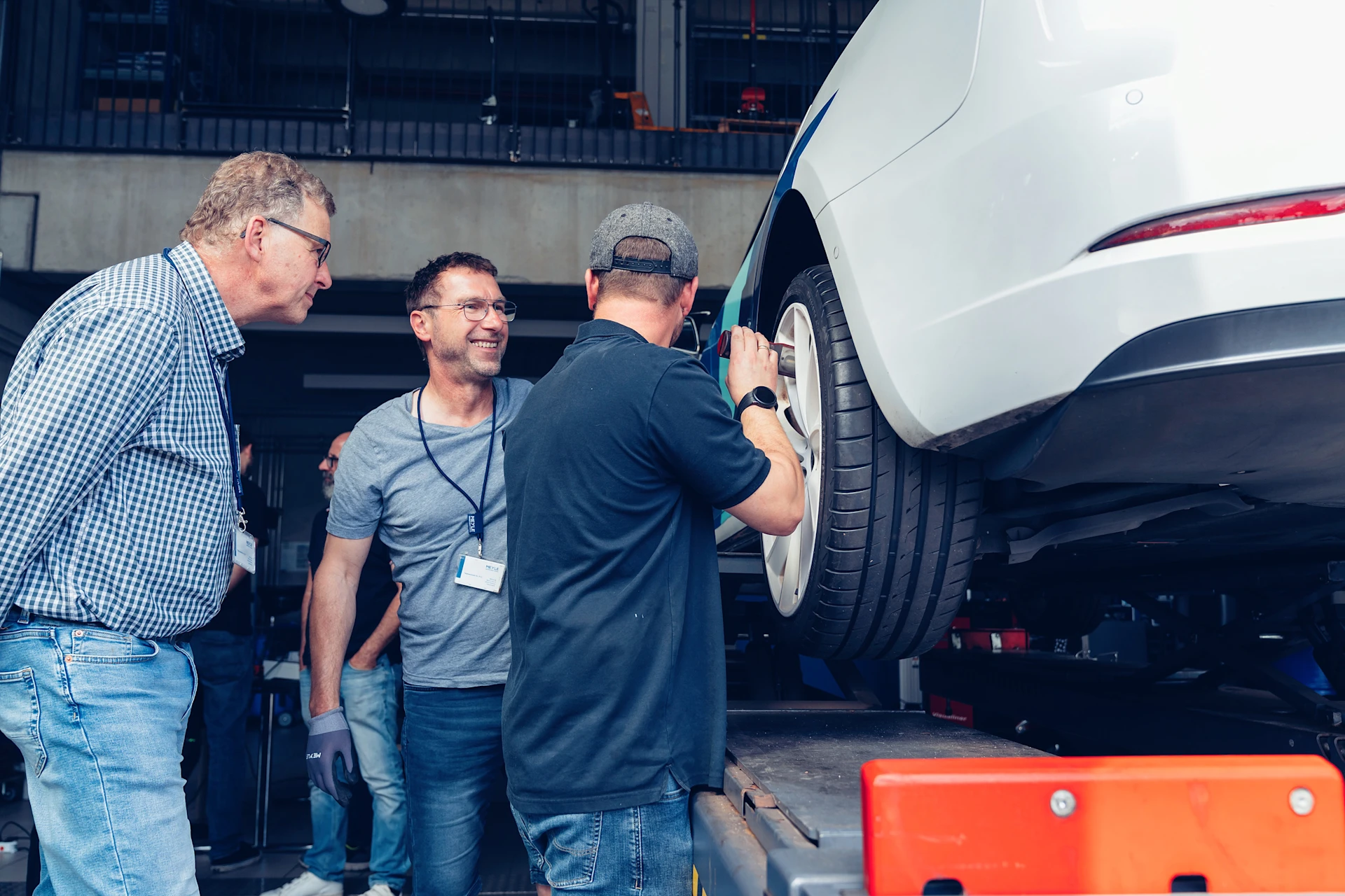 EV Training in der MEYLE Werkstatt. Trainingsteilnehmer schrauben an einem Rad bei einem Elektroauto.